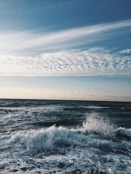 Blue sea wave with white foam and sky in background