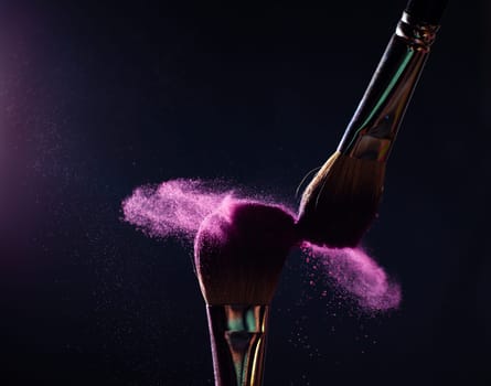 Make-up brush with pink powder explosion on black background