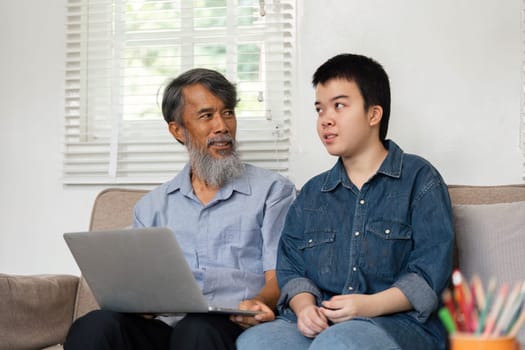 A grandfather shares quality time with his grandchild, who has Down syndrome, as they explore the digital world together. This image showcases love, support, and intergenerational learning.
