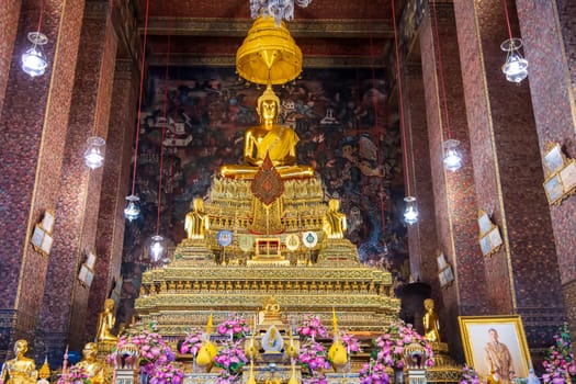 In a peaceful temple, a magnificent golden Buddha statue is surrounded by vibrant, colorful flowers