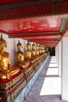 A tranquil corridor in a Buddhist temple, featuring golden statues and a vividly colored red ceiling
