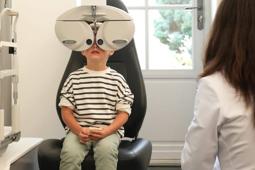 A little boy with ophthalmic equipment in clinic. Children's doctor examining