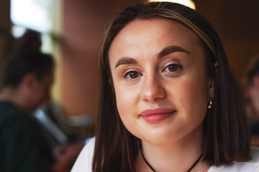 Portrait of a young woman in a coffee shop, brown-haired with short hair and brown eyes. High quality photo