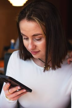 Young woman with phone in coffee shop. High quality photo