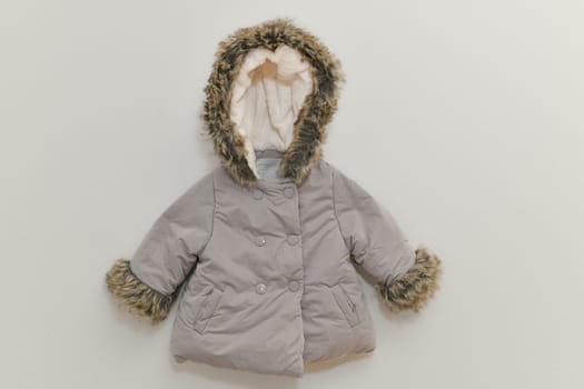 Grey-lilac colored fur jacket for girl hanging on hanger on white background