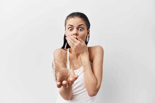 Surprised young woman holding a clump of hair in her hand, covering her mouth in shock Set against a plain white background, the image highlights concerns about hair loss and beauty