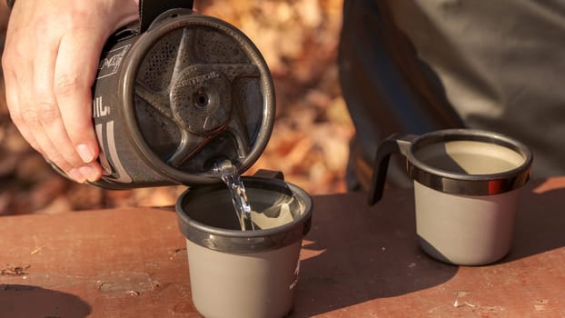 making coffee with boiling water in the autumn wooded forest while camping in an instant boil Jetboil and small gas tank. Ottawa ON Canada - 07.27.2023.