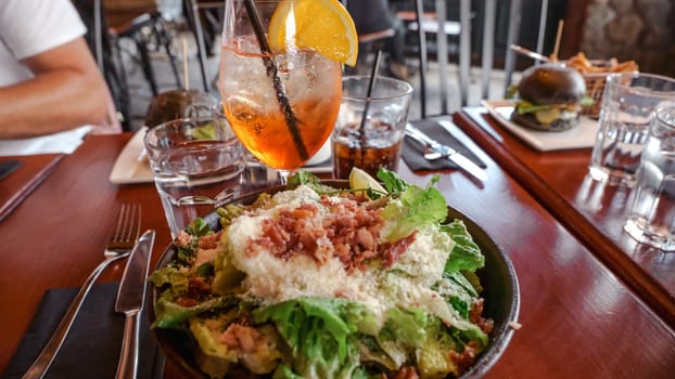 A colorful salad with grilled chicken slices on mixed greens, topped with cherry tomatoes, cucumbers, and bell peppers, drizzled with light vinaigrette, served on a rustic wooden table.