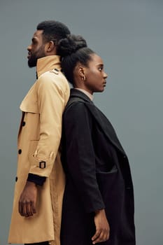 This image features a fashionable couple posing back to back, highlighting contemporary styles and emotions of confidence The muted gray background complements their chic outfits, making it ideal fo