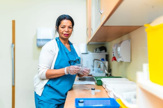 Confident mature female nurse wearing gloves preparing medication in a nursing home treatment room