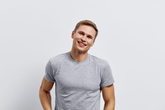 Smiling man young adult casual gray t-shirt portrait cheerful confident positive expression on plain white background studio shot people lifestyle concept