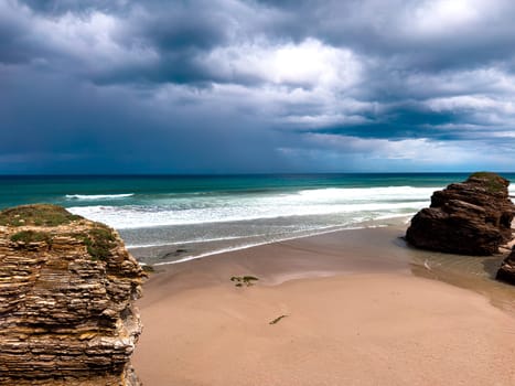 16 april 2025. Lugo, Galicia. Dramatic coastal scene Playa de las Catedrales with rock formations and approaching storm clouds over ocean.