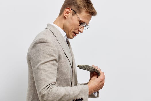 Thoughtful man wearing glasses and a beige blazer examining a worn tablet device, standing against a plain neutral background. The scene conveys concentration, professionalism, and modern technology use, suitable for business and innovation themes