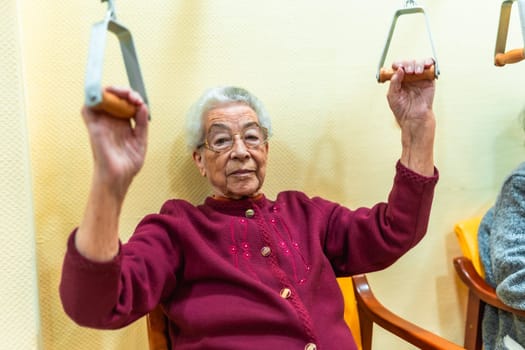 Senior woman performing physical therapy exercises with a pulley machine, promoting mobility and well being in a nursing home environment