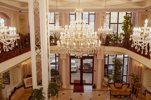 Odessa, Ukraine - February 26, 2025: California Hotel. Luxurious hotel lobby with crystal chandeliers, antique furniture in the lobby. High panoramic windows, marble floor and mirrors on the walls