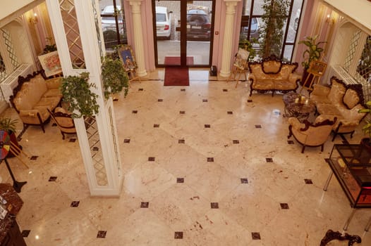 Odessa, Ukraine - February 26, 2025: Hotel California. Luxurious hotel lobby with antique furniture, high panoramic windows, marble floor and mirrors on the walls, interior design in gold tones
