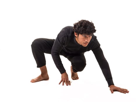 A young man poses on a white background, displaying agility and strength. His intense expression highlights focus while his bare feet suggest a connection to movement and freedom.