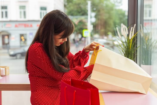 Woman exploring purchases in colorful shopping bags. Concept of consumption and lifestyle leisure.
