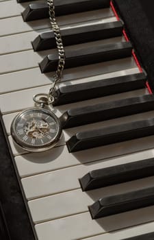 London, UK - Apr 19, 2025 - Antique pocket watch or Retro pocket watch on Piano keys background. "keys and time" use it as your Wallpaper, Poster and Space for text, Selective focus.
