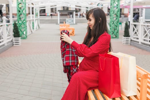 Woman smiles while reaching into shopping bag. Joy of shopping and discovering new purchases.