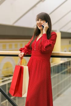 Woman talks on phone while shopping in mall. Communication and joy during shopping moments indoors.