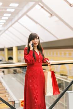 Woman talks on phone while shopping in mall. Communication and joy during shopping moments indoors.