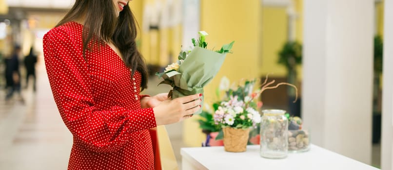 Woman choosing flowers while shopping in mall. Leisure, beauty and lifestyle theme