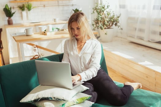 Woman working remotely on laptop at home. Freelance, remote work and modern lifestyle concept