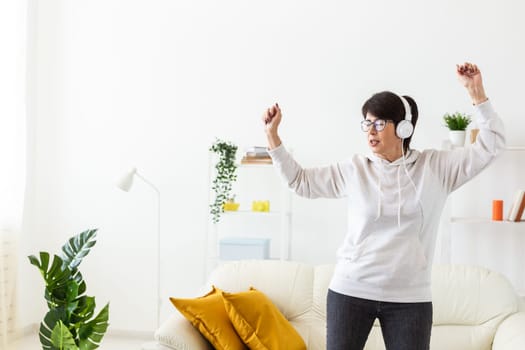 Joyful woman listening to music and dancing at home. Freedom, relaxation and happiness concept