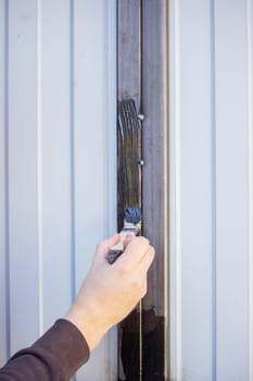 close-up of a man painting metal black with a brush.painting