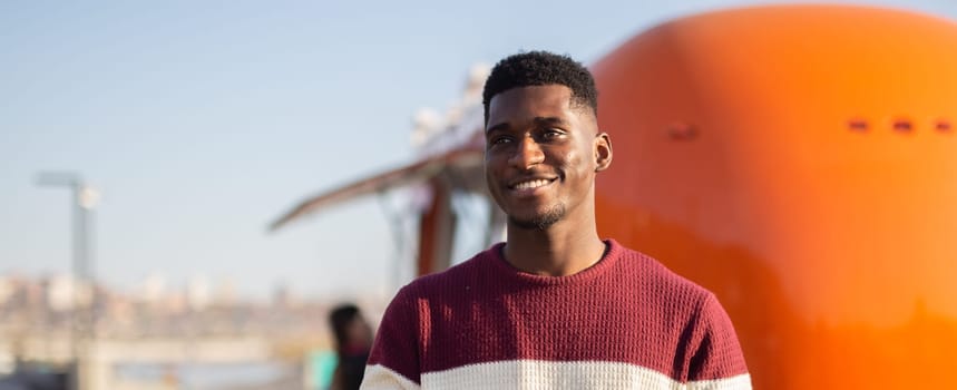 African american man smiles on a sunny city day. Concept of happiness, relaxation, travel and urban lifestyle.