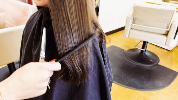 Gentle hands maneuver a hair dryer through a young girl's newly cut hair, showcasing the drying process after a meticulous trim. The warmth of the dryer breathes life into her locks, as they transform from damp to styled with care and expertise.
