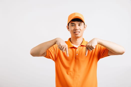 Portrait Asian smiling young delivery man pointing down something with empty space hands studio isolated white background, Happy lifestyle men carry person in an orange shirt uniform point finger