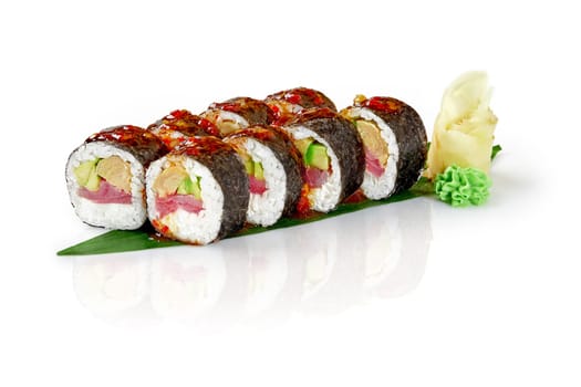 Fresh sushi rolls with tuna, avocado, omelette, and a spicy sauce, served on a bamboo leaf with wasabi and ginger