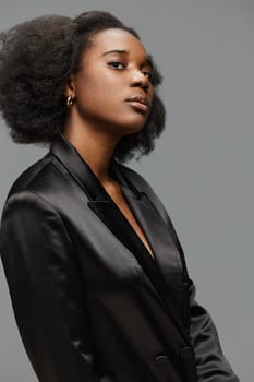 A poised Black woman showcasing a fashionable black satin blazer, radiating confidence and elegance with her natural hair, ideal for beauty, fashion, or empowerment themes