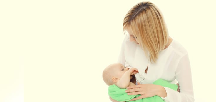 Happy young mother breastfeeding her baby on white studio background