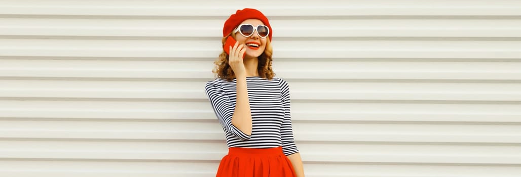 Beautiful happy smiling young woman calling on phone, stylish girl talking on the smartphone in red skirt, french beret hat on white background