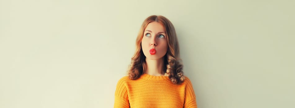 Pensive caucasian young woman thinks looking away, red lipstick, on studio background, blank copy space