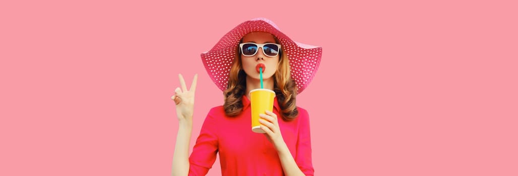Summer portrait of beautiful young woman drinking fresh juice wearing straw hat, pink dress on studio background
