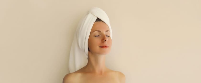 Natural beauty portrait of happy young caucasian woman enjoying her clean skin drying wet hair with white bath towel on her head