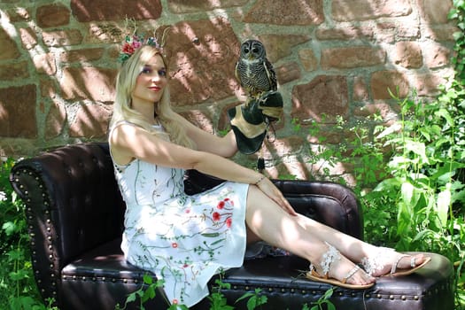 A woman dressed as an elf holds a tawny owl on her hand