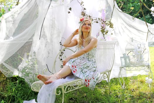 A woman dressed as an elf lies smiling on a bed with white curtains