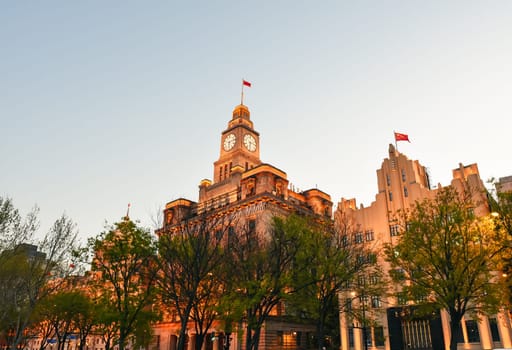 Shanghai, China - 1 April 2025: The Bund at sunset with historic Shanghai Customs House and art deco AIA Building glowing against golden sky