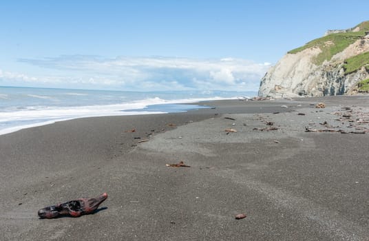 Waves crash onto South Pacific beach lined with cliffs bin New Zealand leading white foam wash as they flow back.