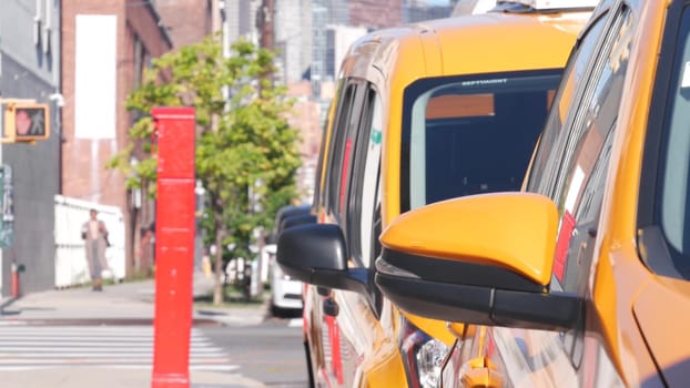 New York City, United States - 1 Sept 2023: Row of yellow Taxi cars on street, Queens. Many taxi cabs in Long Island. Medallion taxicab on road and red police telephone kiosk. Callbox in Hunters Point
