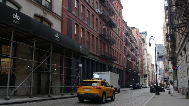 New York City, United States - 8 Sept 2023: Manhattan Soho fashion district near Broadway street. USA urban building facade, old classic american architecture. Shopping in NYC. People, yellow taxi cab