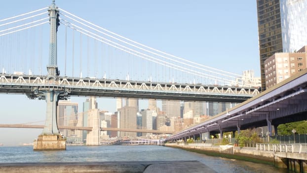 New York City, United States - 7 Sept 2023: Manhattan Bridge to Brooklyn. Waterfront downtown skyline cityscape, financial district skyscrapers from riverfront Pier 35. East river morning sunset.