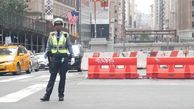 New York City, United States - 29 Aug 2023: Manhattan Midtown 34 street, Madison avenue crossroad intersection. Urban road in USA. Traffic Control Police guard or NYPD flagger. Yellow taxi car, people