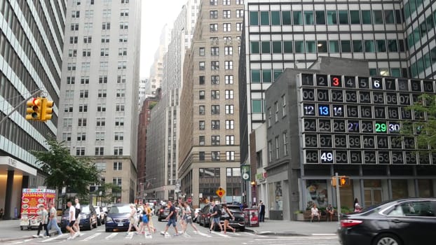 New York City, United States - 9 Sept 2023: Manhattan Downtown Financial District Water and John street crossroad intersection. USA road car traffic. Yellow taxi, people. Digital clock, bingo board.