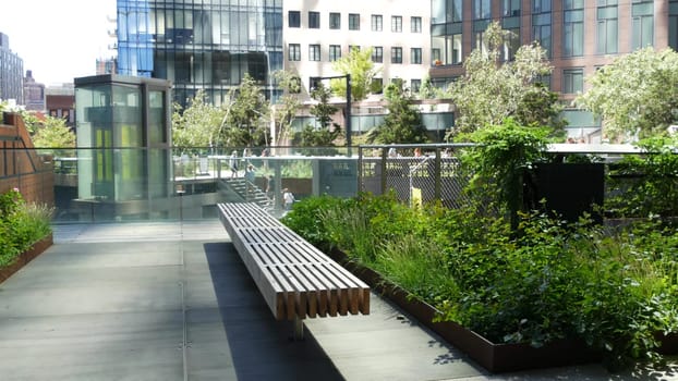 New York City, United States - 1 Sept 2023: High Line elevated greenway, Manhattan Midtown, USA. People in park. Promenade in garden greenery. American street life, Chelsea Hudson Yards. Wooden bench.